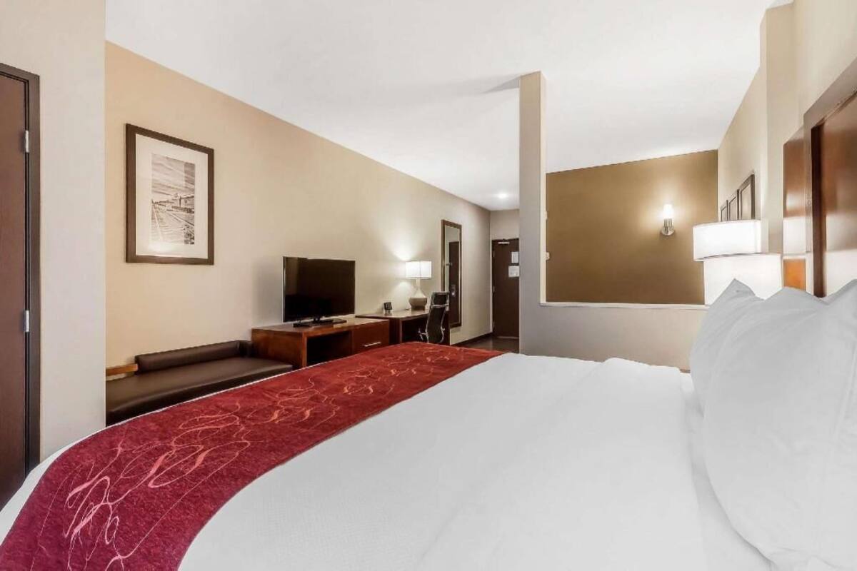 Ein Hotelzimmer mit einem Bett, einem Schreibtisch, einem Sessel, einem Fernseher und einer Wandleuchte.