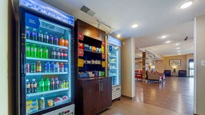 Un hall d’hôtel comprenant des distributeurs automatiques, un comptoir d’accueil et un espace détente avec des sièges.