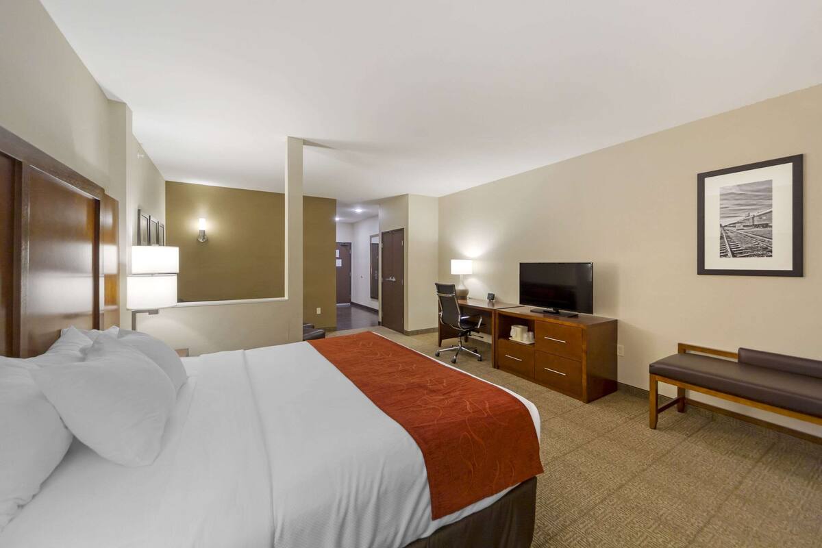 Ein Hotelzimmer mit Bett, Schreibtisch, Fernseher und einer Sitzbank.