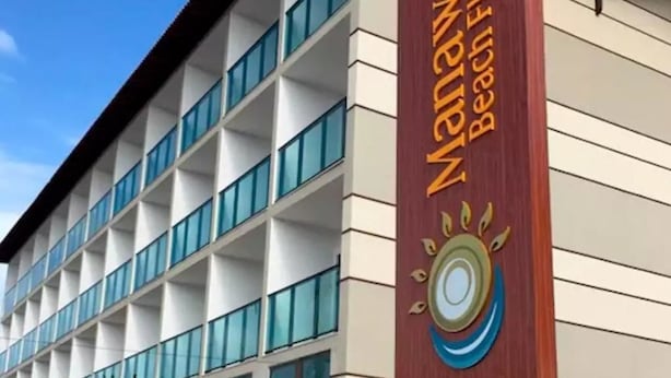 Un edificio de hotel de varios pisos con un letrero que dice "Manawa Beach Flat".