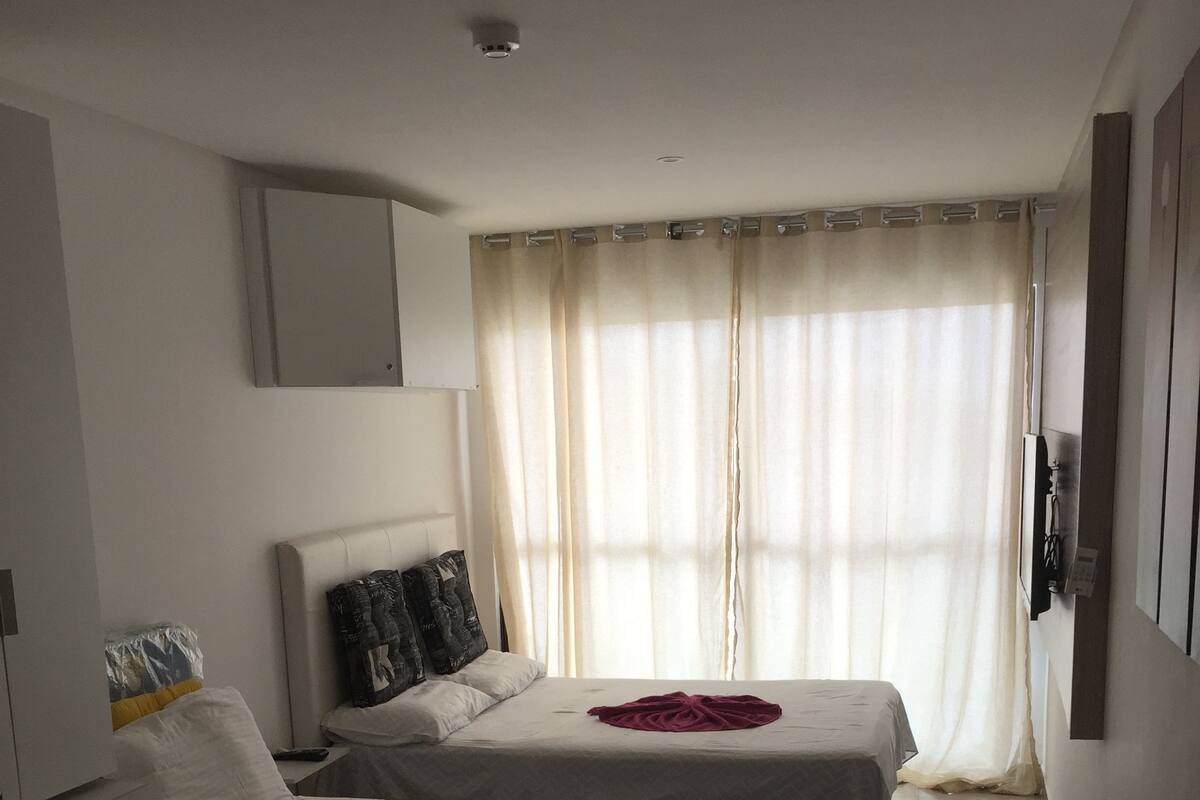 A bedroom with two beds, a desk, and a TV.