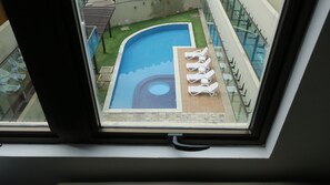 Une vue d’une piscine avec des chaises longues et un petit espace circulaire aménagé en jacuzzi.