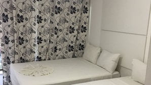 Una habitación de hotel con dos camas, cortinas florales y un cabecero.