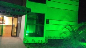 Un edificio de varios pisos con una entrada iluminada en verde y una entrada a nivel de calle visible.