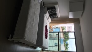 Una habitación con cama, ventana y vistas a edificios.