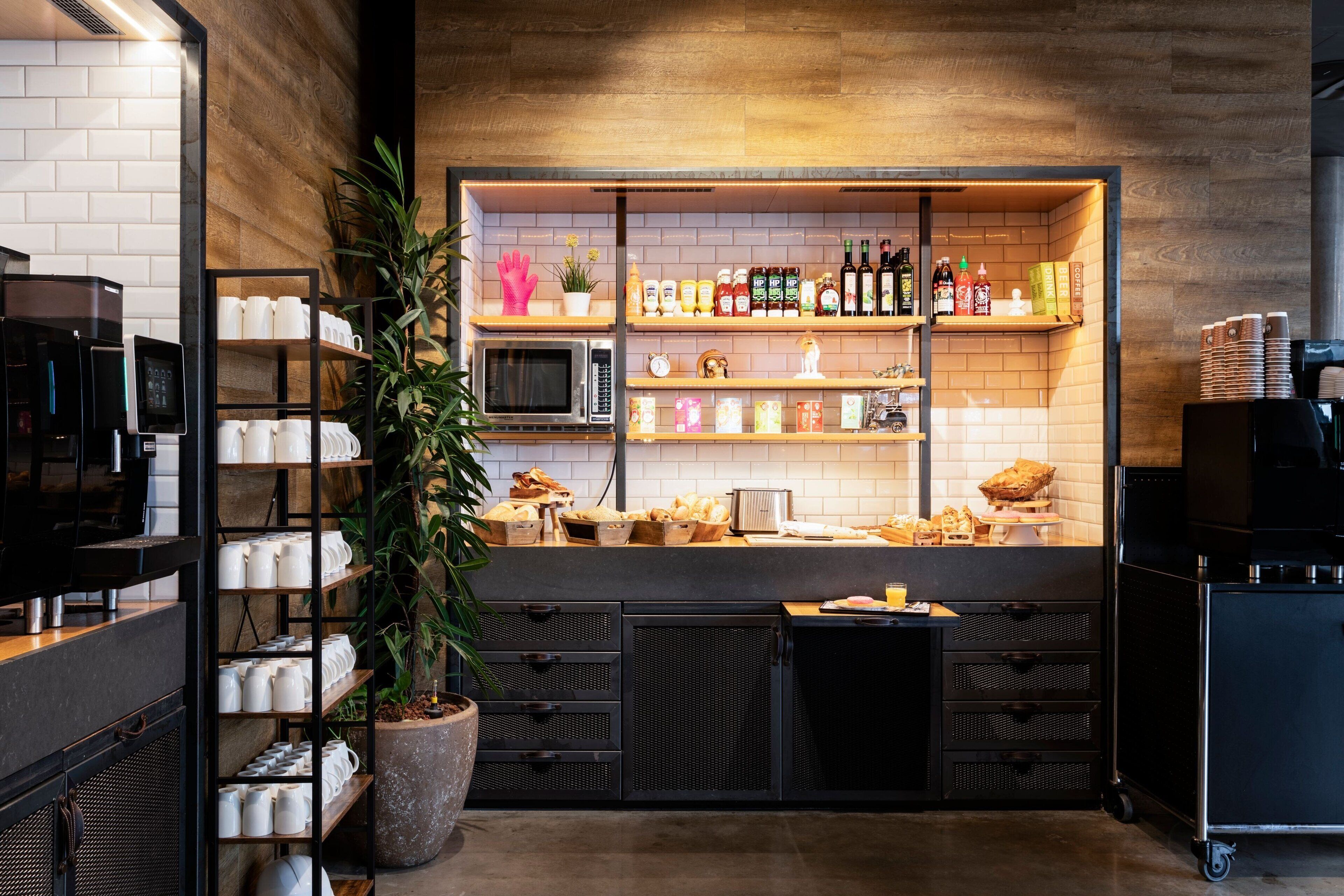Una cocina con cafetera, estantes con diversos objetos y una planta en maceta.