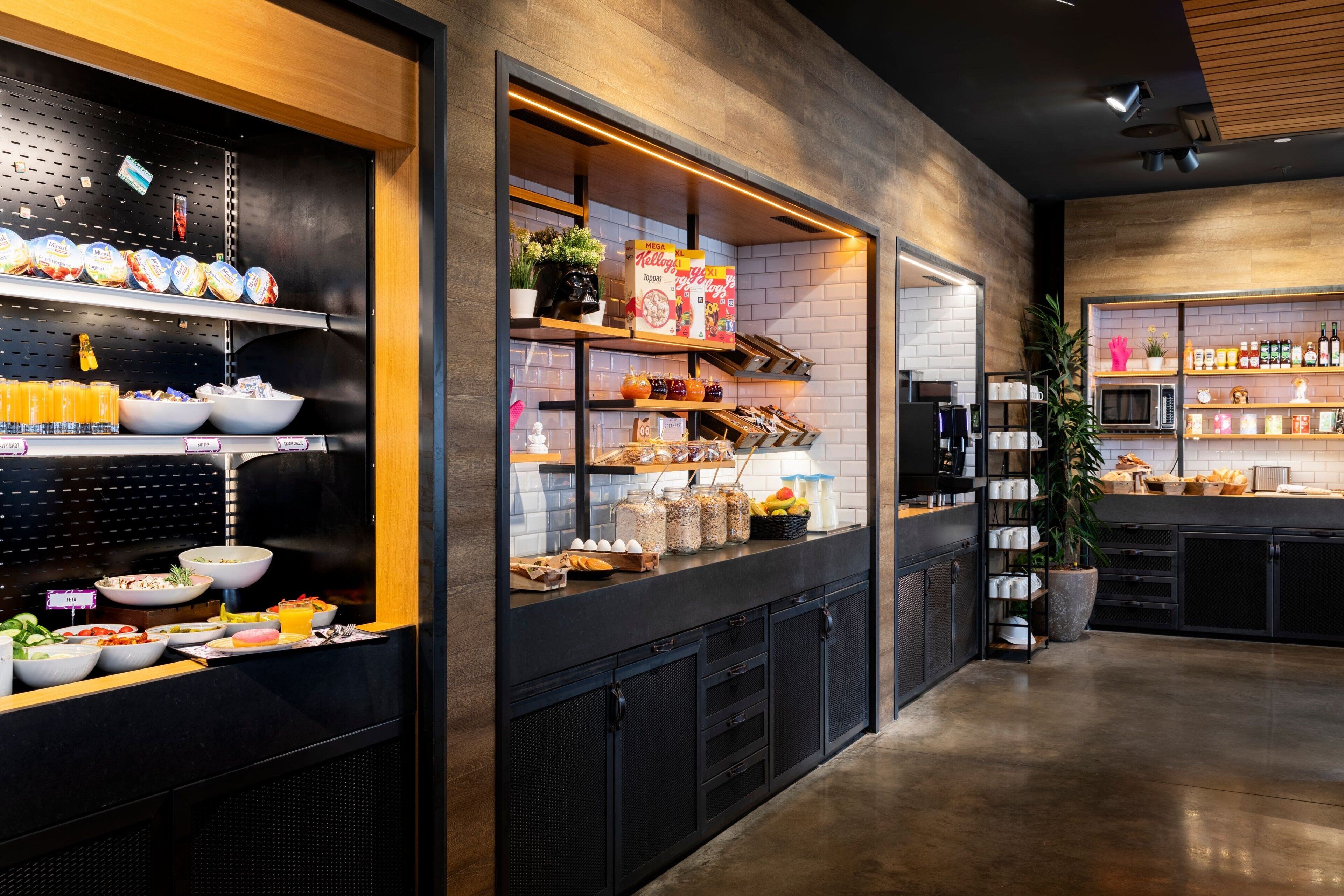 A modern kitchen area with shelves stocked with food items, a microwave, and various kitchen appliances.