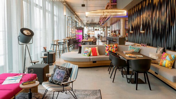 Een moderne zithoek met een bank, fauteuils, een tafel en een vloerlamp.