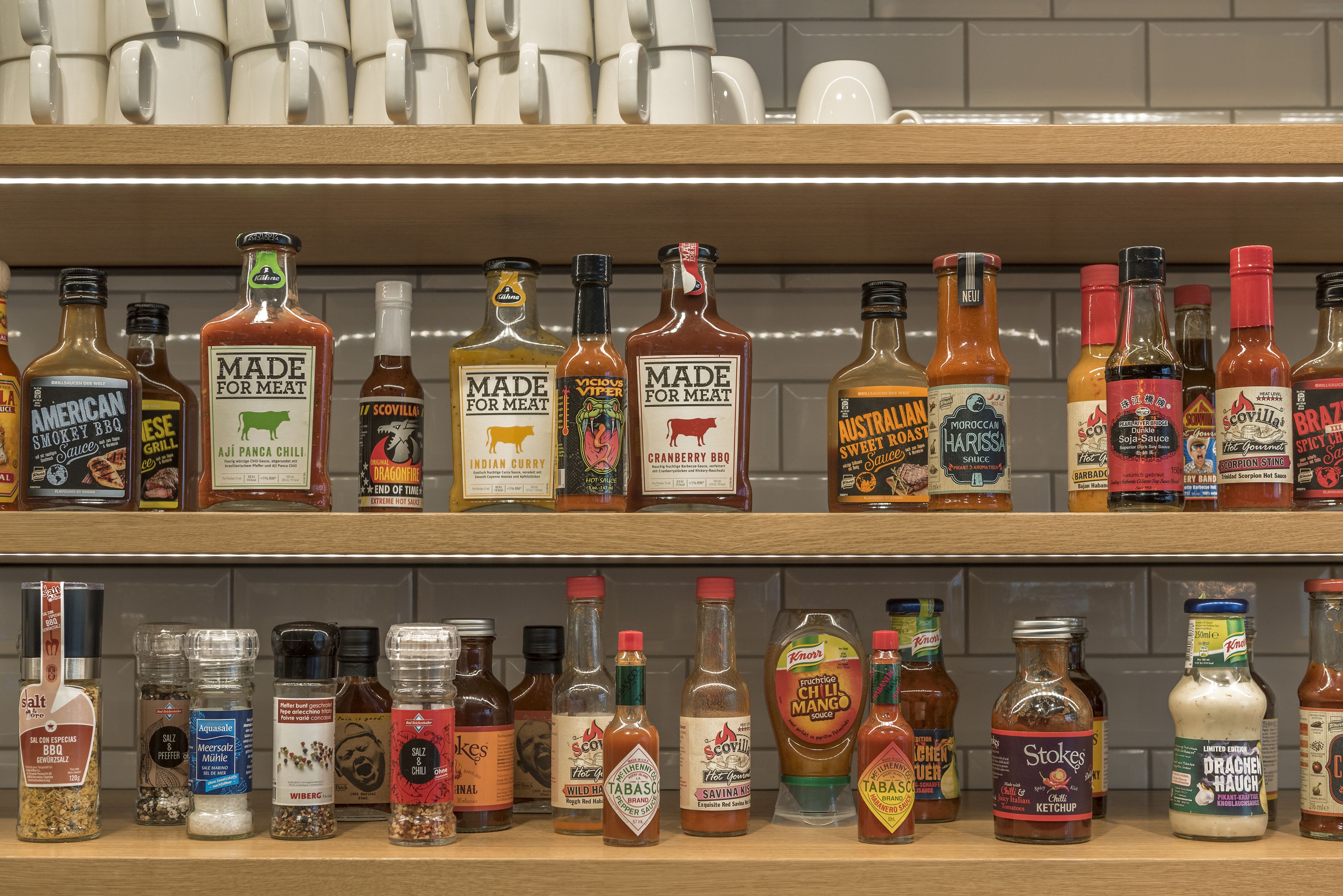 Variedad de condimentos y salsas en estantes, incluyendo marcas como American Smokey BBQ, Made for Meat y Tabasco.