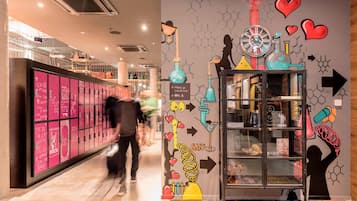 Un couloir avec des casiers, une vitrine contenant des objets scientifiques, et un mur orné de structures moléculaires et de cœurs.