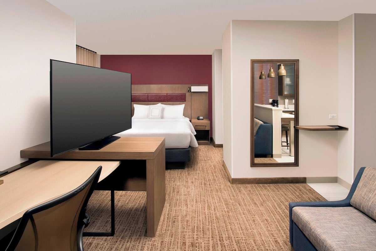 A hotel room with a bed, a TV, a desk, and a sofa.