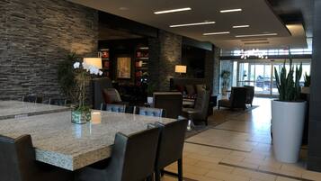 A modern interior with a stone wall, a dining area with a granite table, and a seating area with leather chairs.