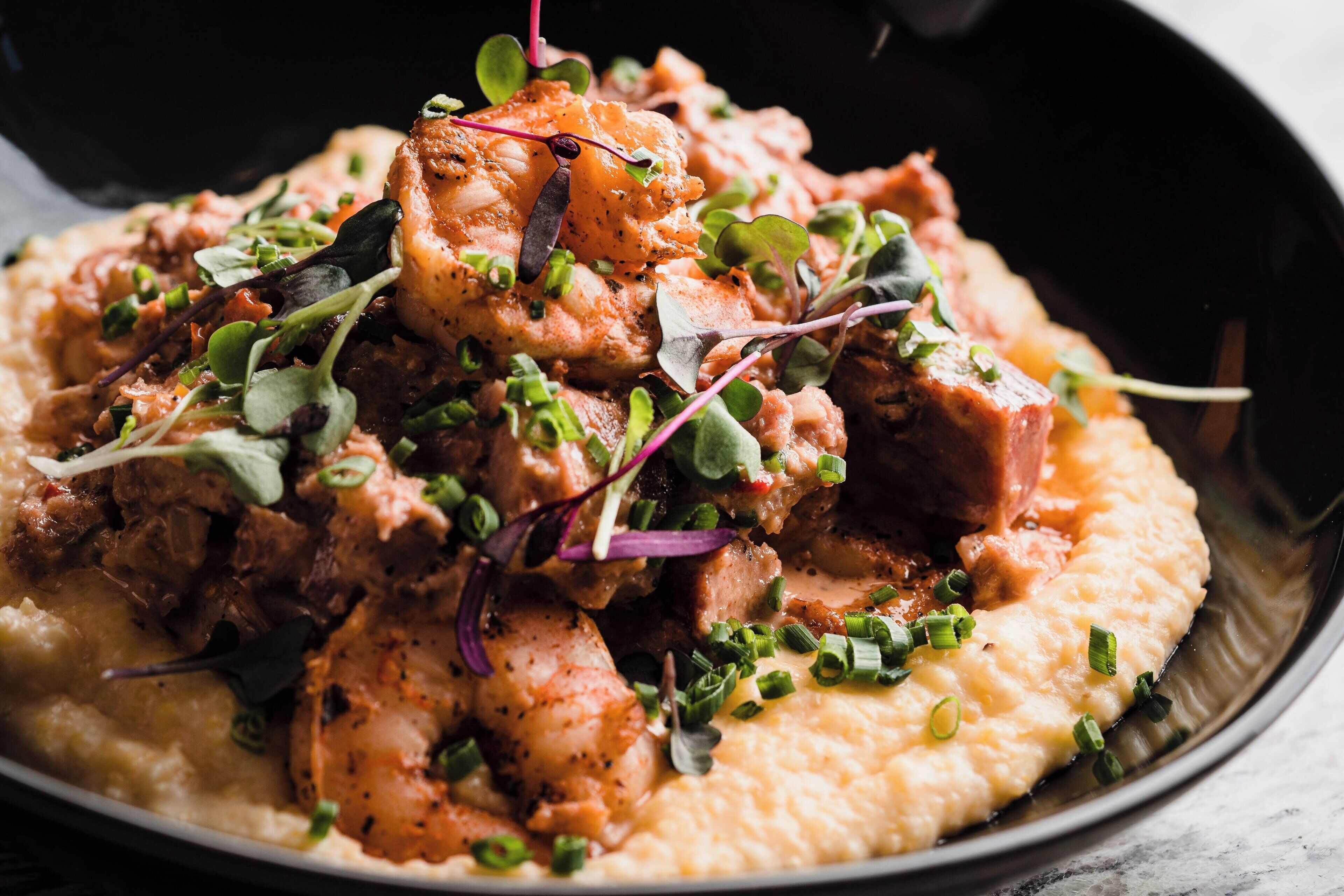 A dish with seafood and greens on a bed of mashed potatoes.