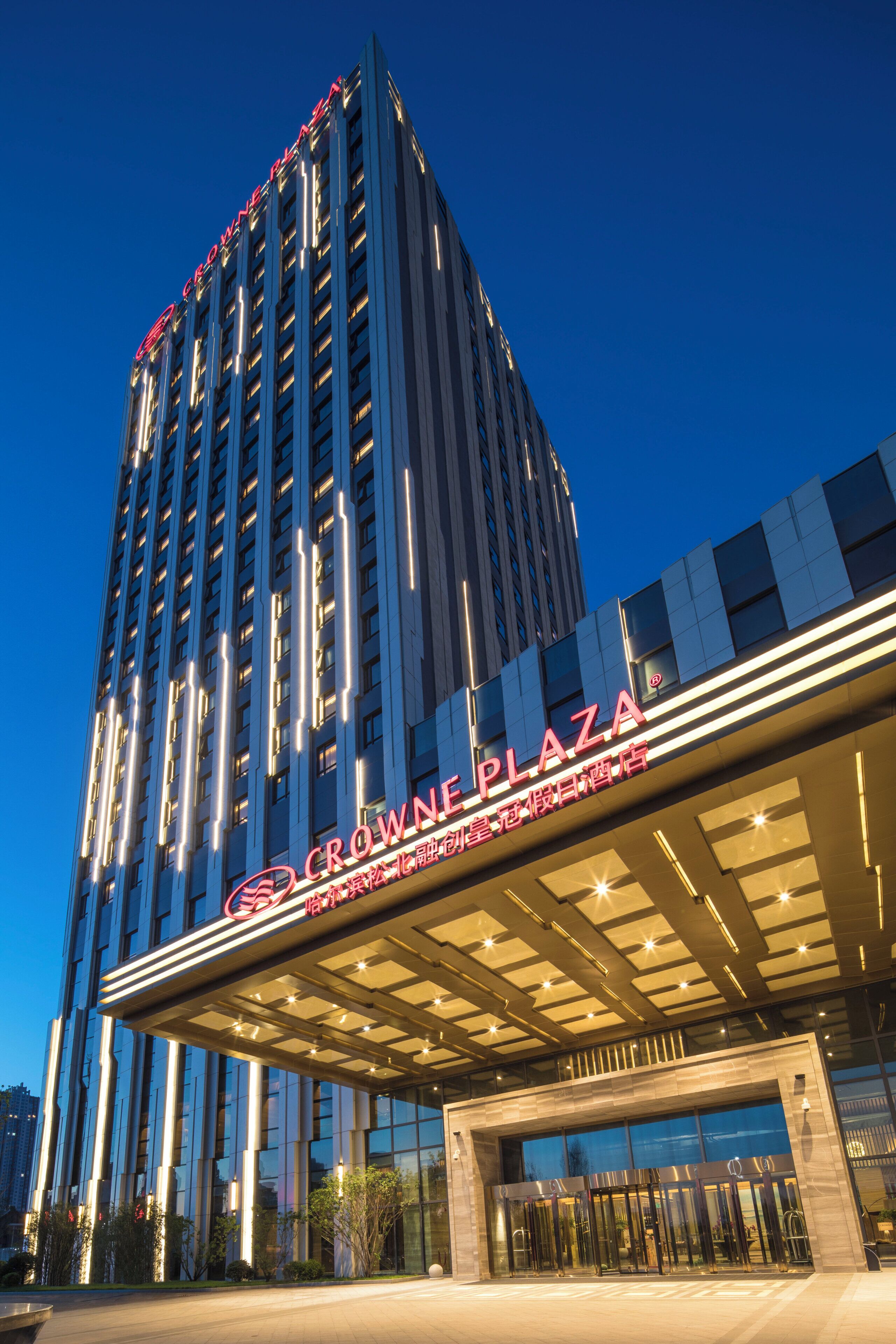 A high-rise hotel building with a prominent sign for 'Crown Plaza' and a modern entrance with glass doors.