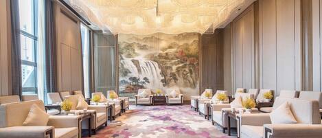 Un vestíbulo de hotel con un amplio espacio de estar, un mural de cascada y una alfombra estampada.