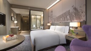 A modern hotel room with a large bed, a desk with a computer, a flat-screen TV, and a bathroom visible through an open door. - Crowne Plaza Harbin Songbei by IHG (Harbin)