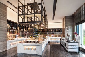 A modern restaurant with a central serving area, multiple food stations, and a visible kitchen area. - Crowne Plaza Harbin Songbei by IHG (Harbin)