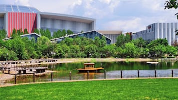 A modern building with a glass facade, a body of water with a boat, and a grassy area.