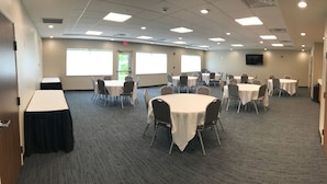 A conference room with multiple tables and chairs, large windows, and a flat-screen TV on the wall. - Holiday Inn Express and Suites Portage by IHG (Portage)