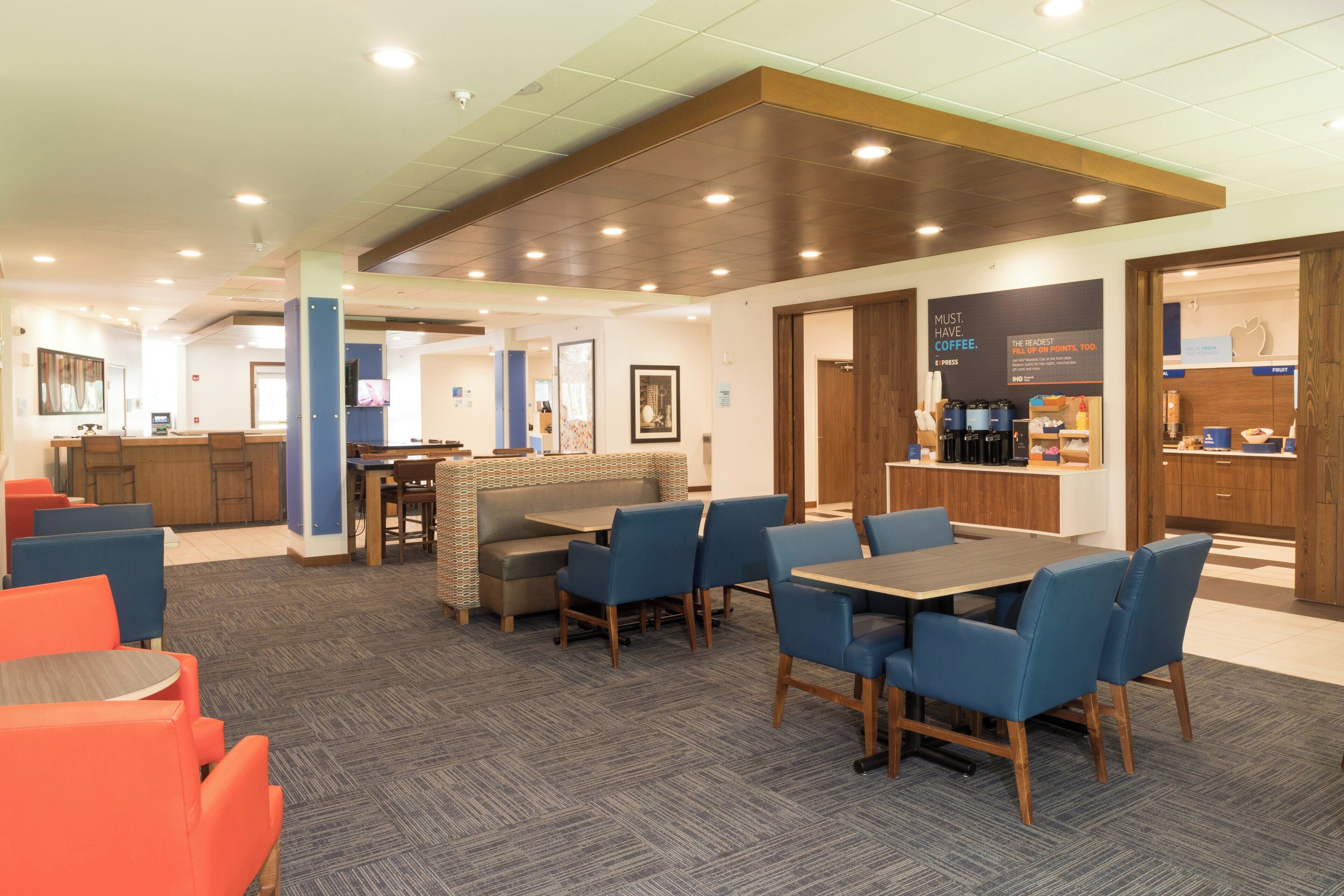 A modern hotel lobby with a seating area, a coffee station, and a counter.