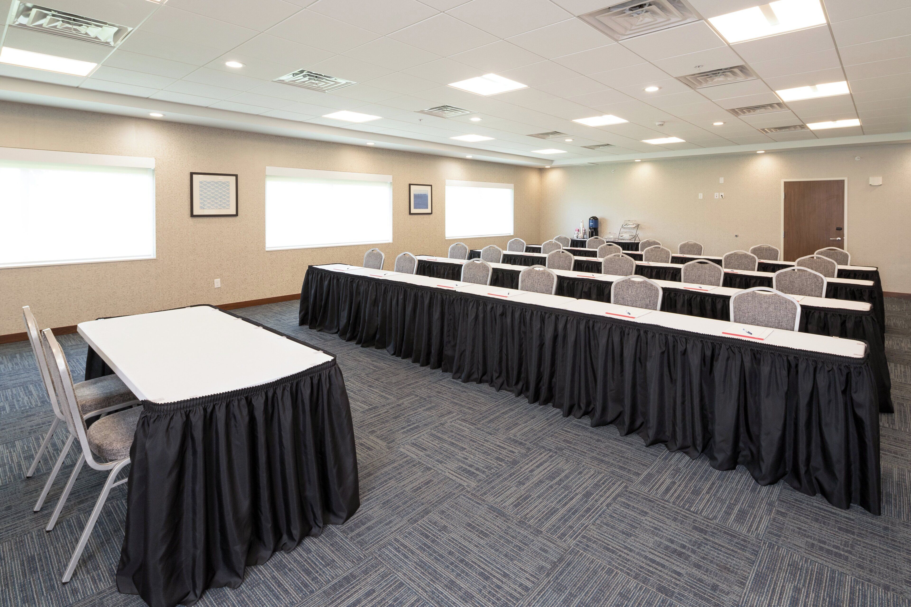 A conference room with a long table, chairs, a projector screen, and a whiteboard.