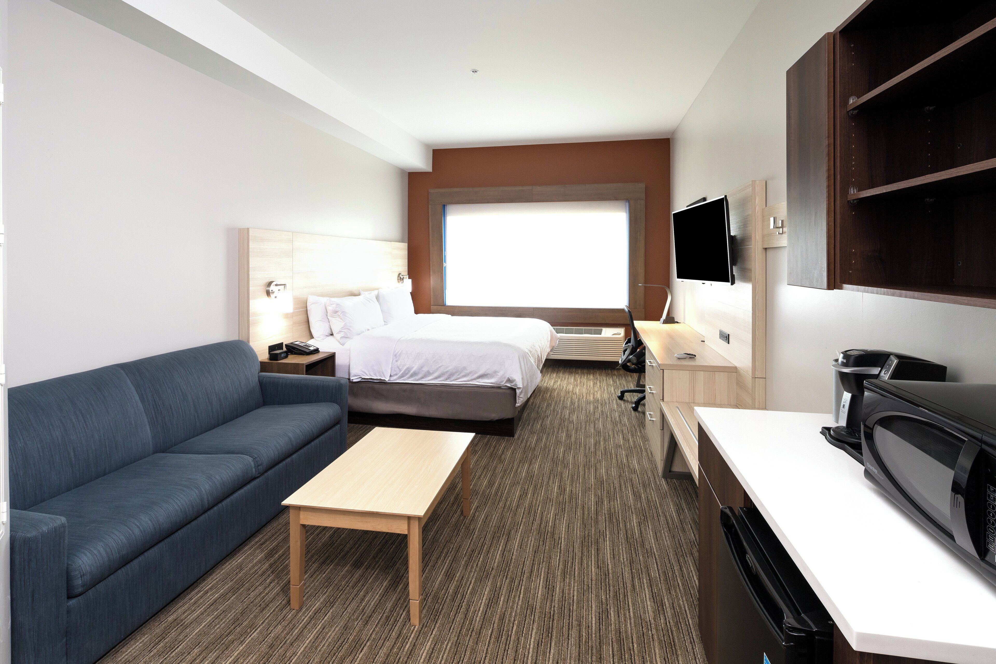 Una habitación de hotel con cama, sofá, escritorio, televisión y cafetera.