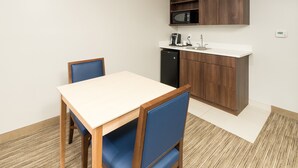 A compact kitchen with a microwave, coffee maker, and sink, and a dining area with a table and chairs. - Holiday Inn Express and Suites Portage by IHG (Portage)