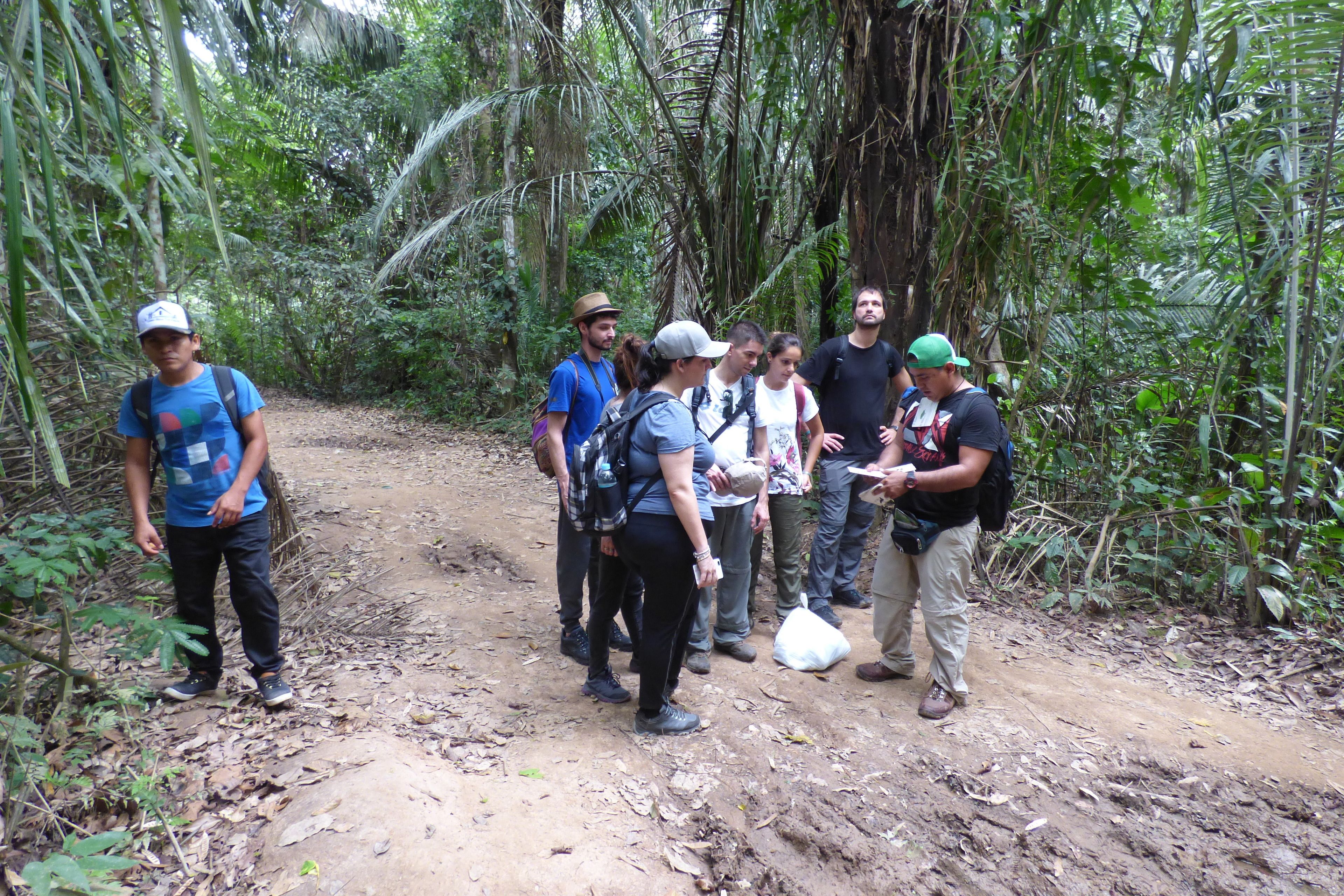 A group of people standing on a dirt path in a forested area.