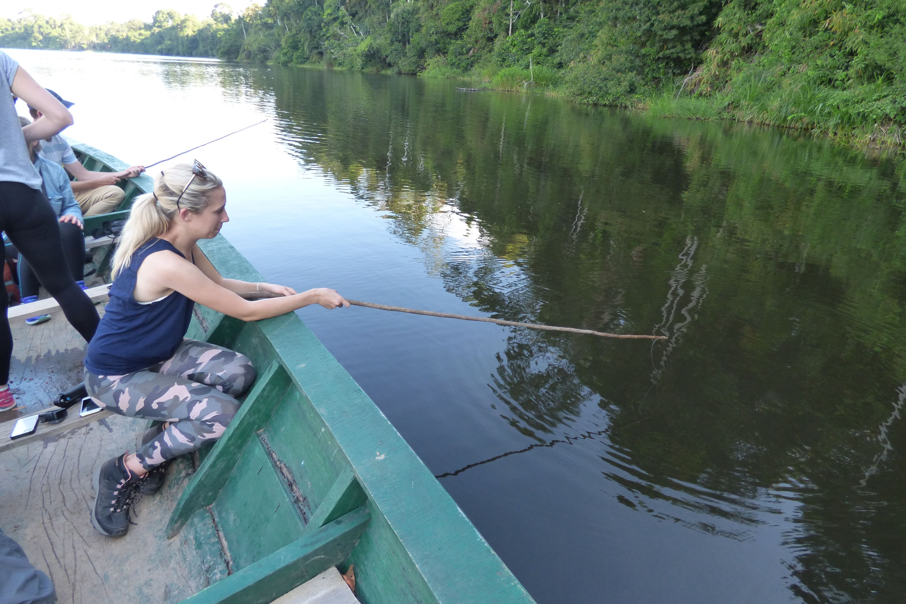 Une personne est en train de pêcher depuis un bateau vert.