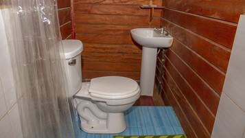 A small bathroom with a toilet, sink, and wooden walls.