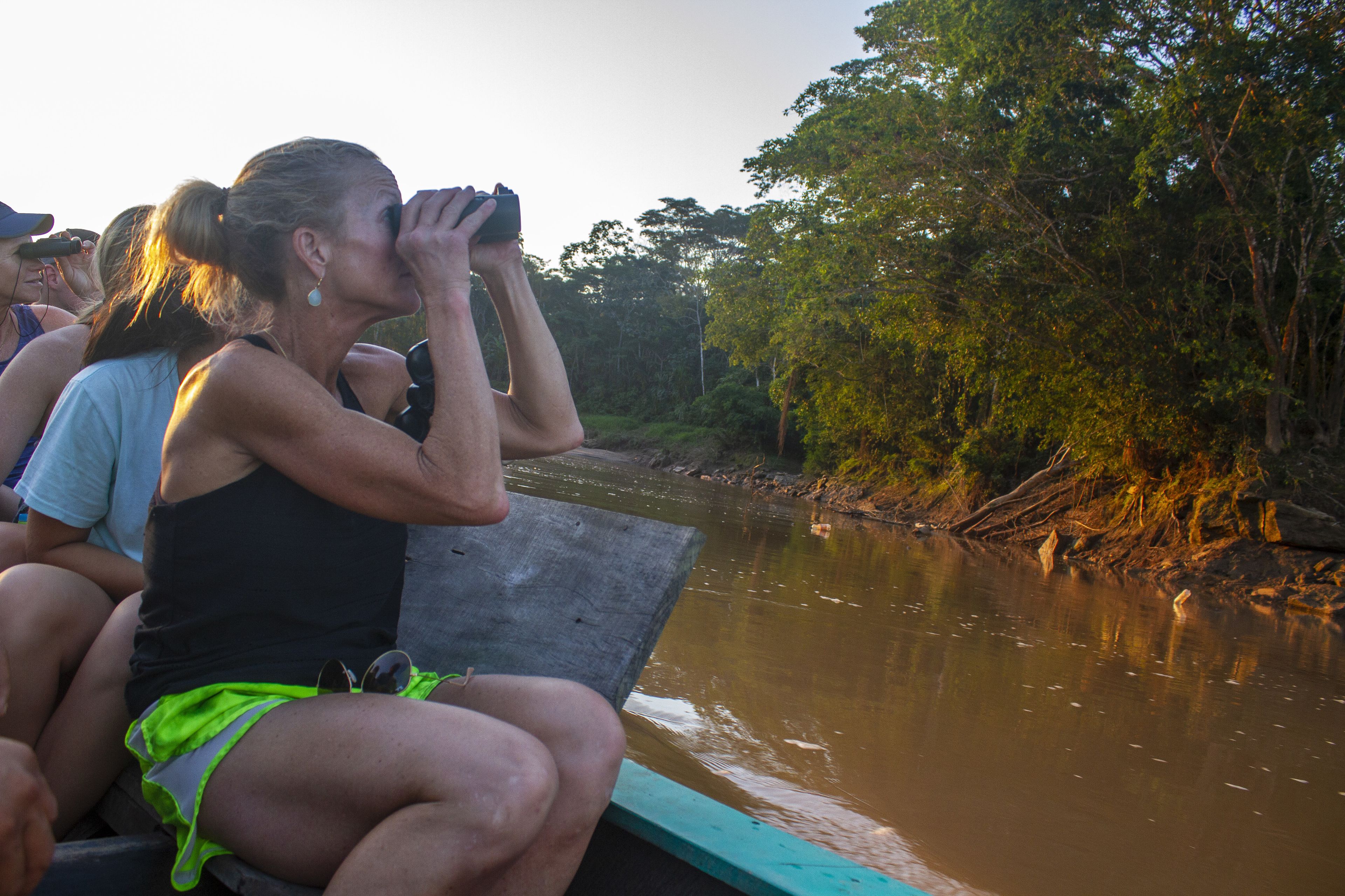 Un grupo de personas en un bote cerca de un río, con árboles en sus orillas.