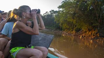 Un grupo de personas en un bote cerca de un río, con árboles en sus orillas.