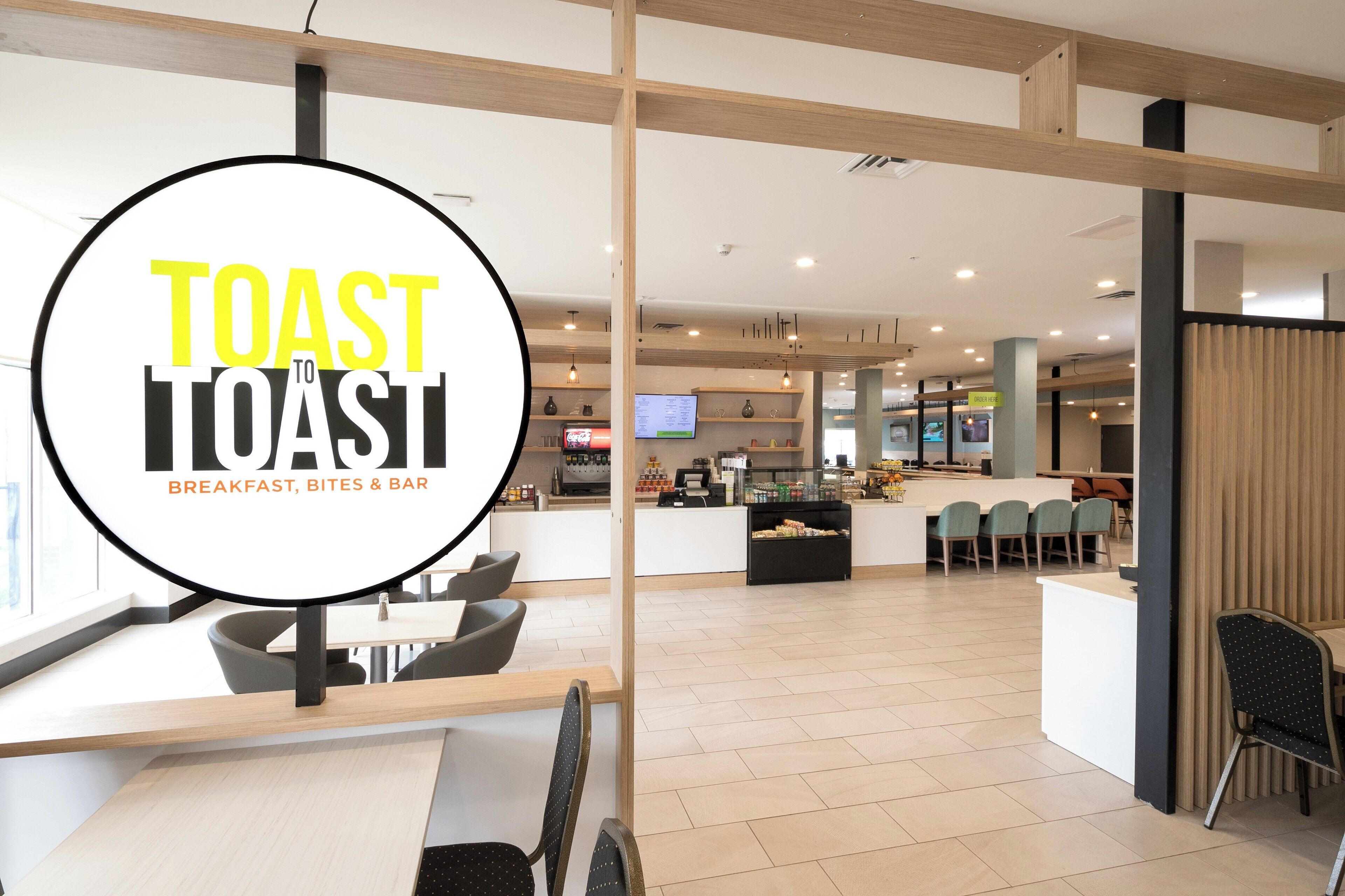 A modern restaurant interior with a central counter, seating area, and a visible menu board.
