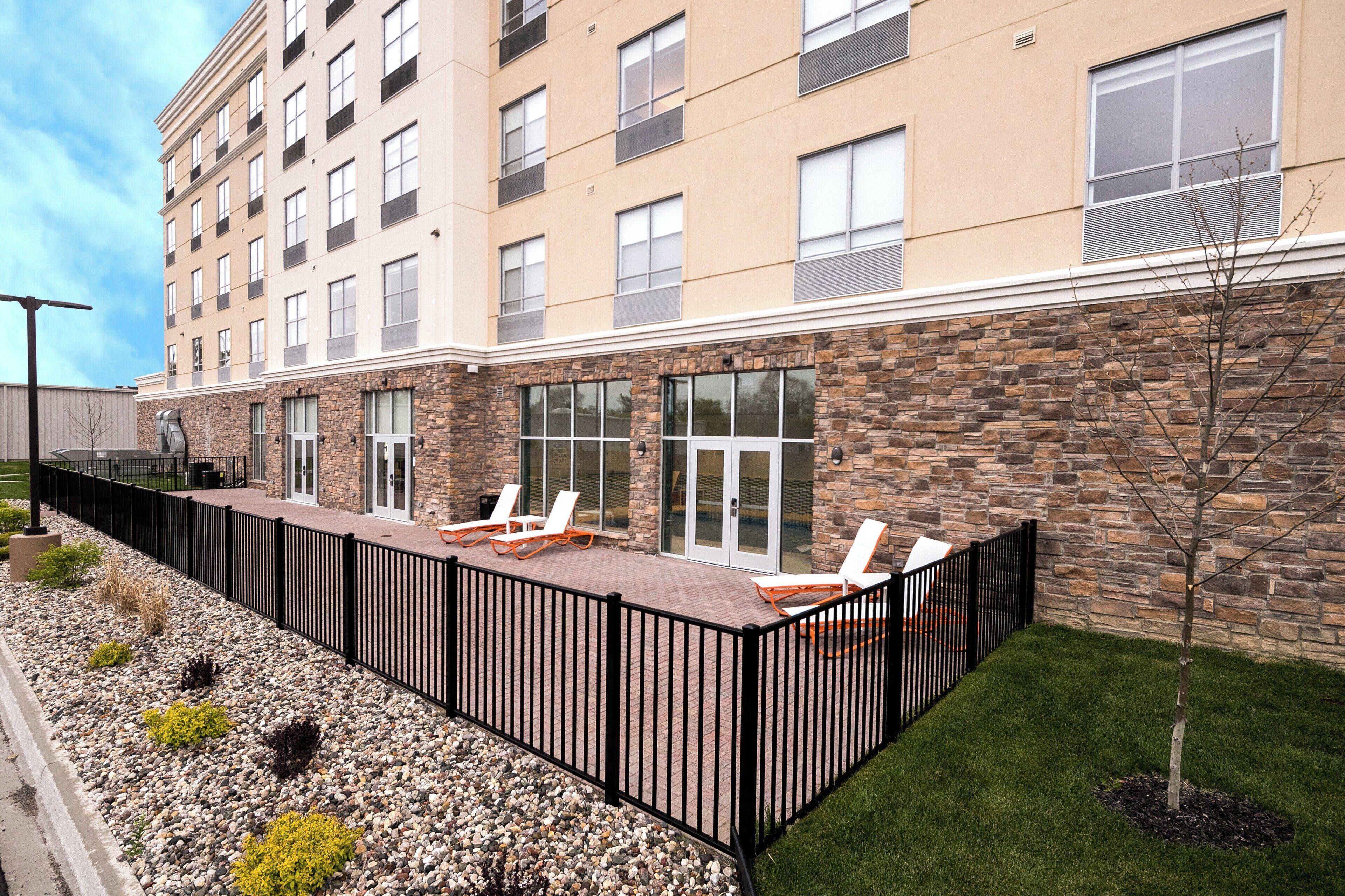 A hotel with a stone facade, outdoor seating area, and a fenced patio.