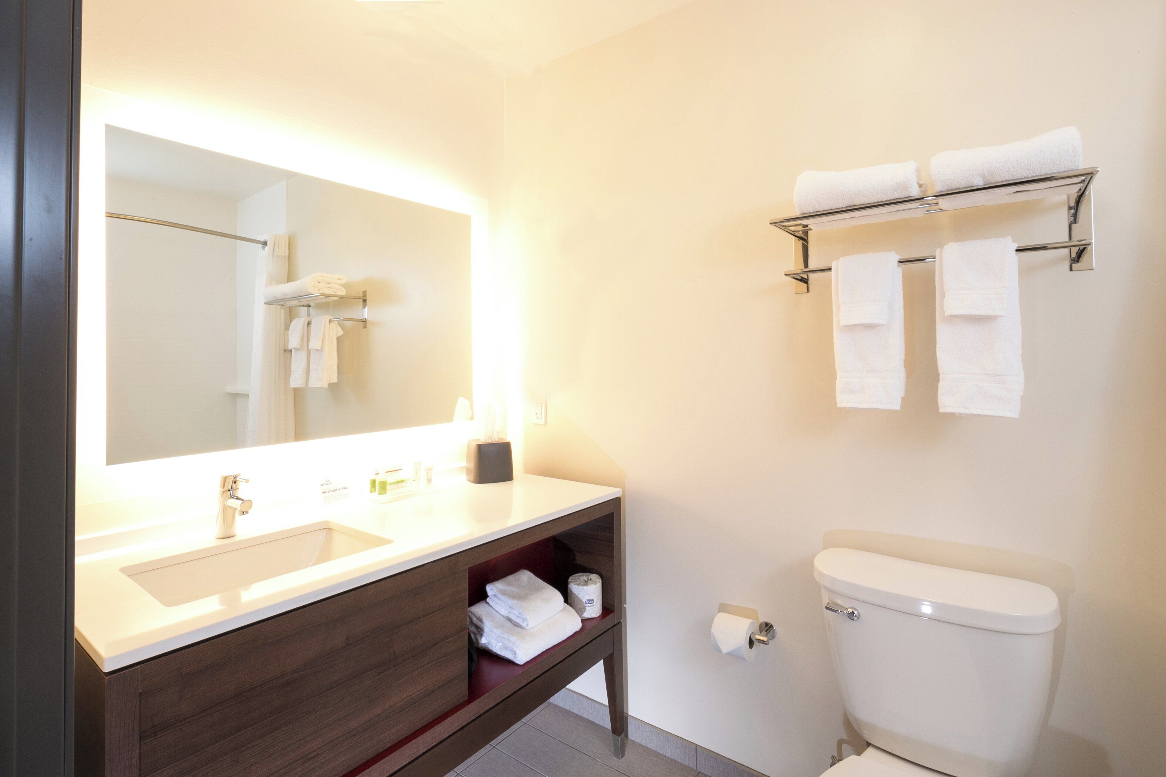 Un baño moderno con un espejo grande, un lavabo, un inodoro y un perchero para toallas.