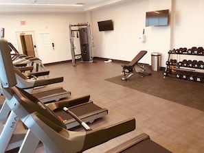 A fitness center with treadmills, a weight bench, a squat rack, and a rack of dumbbells. - Holiday Inn Hotels and Suites Mount Pleasant by IHG (Mount Pleasant)