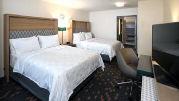A hotel room with two beds, a desk, a chair, and a television.