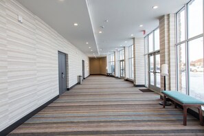 A corridor with patterned walls, a bench, and large windows. - Holiday Inn Hotels and Suites Mount Pleasant by IHG (Mount Pleasant)
