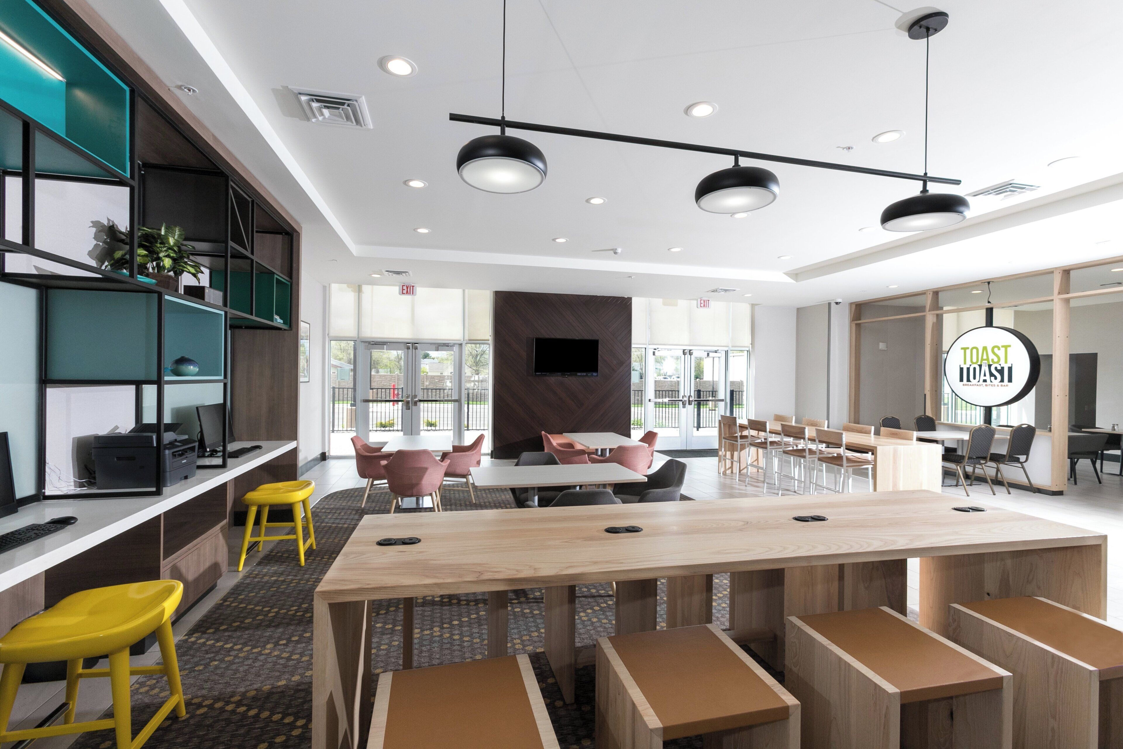 A modern conference room with a long table, multiple chairs, and built-in shelving.