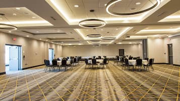 A conference room with multiple tables and chairs, a patterned carpet, and modern circular ceiling lights.