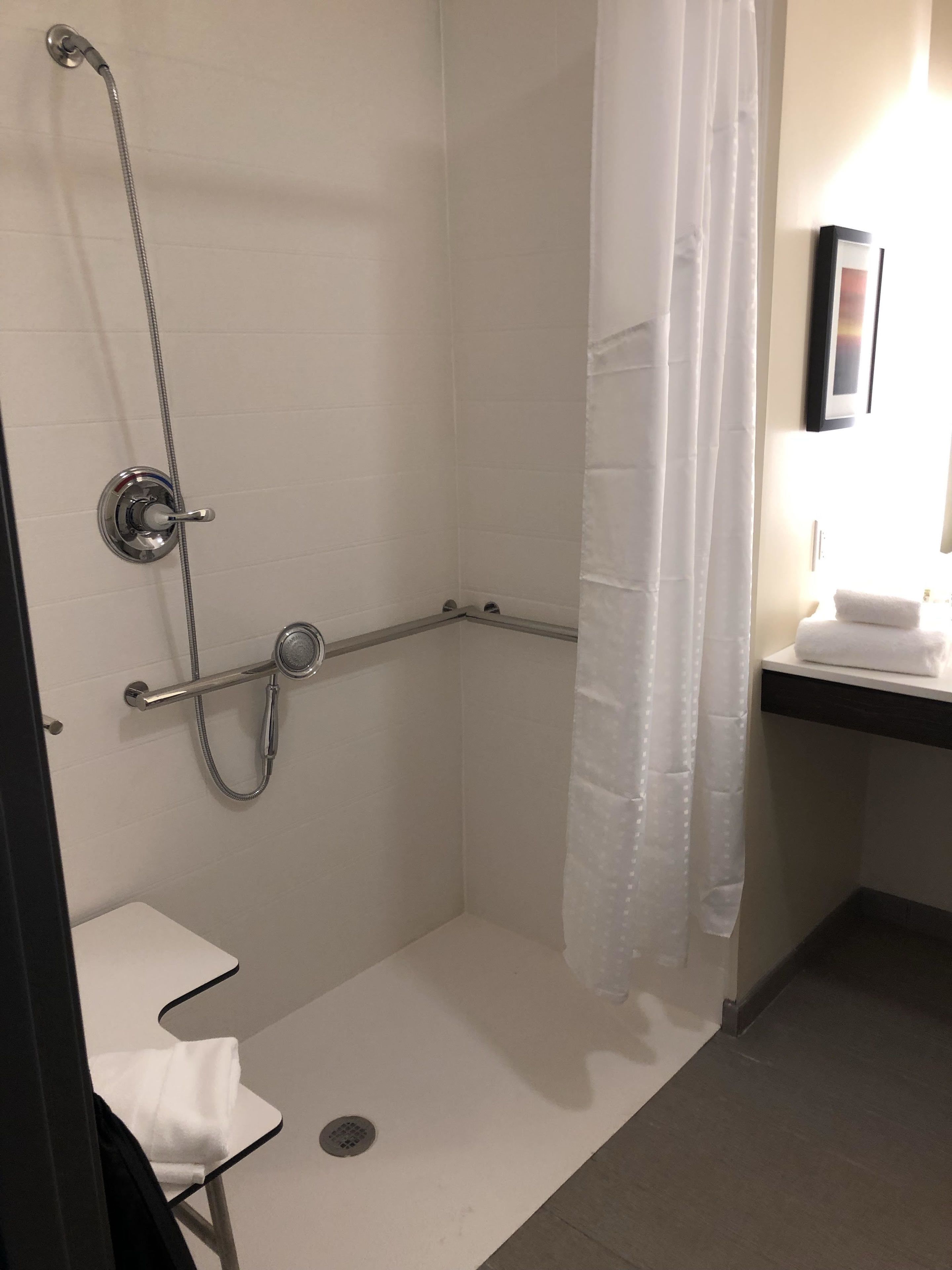 A small, modern bathroom with a walk-in shower, a toilet, and a sink.