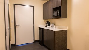 Una kitchenette compacta con microondas, cafetera y lavavajillas.