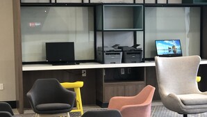 Un espacio de oficina moderno con zona de escritorio, varias sillas y un ordenador portátil que muestra una vista panorámica.