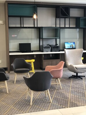 A modern office space with a desk area, multiple chairs, and a laptop displaying a scenic view. - Holiday Inn Hotels and Suites Mount Pleasant by IHG (Mount Pleasant)