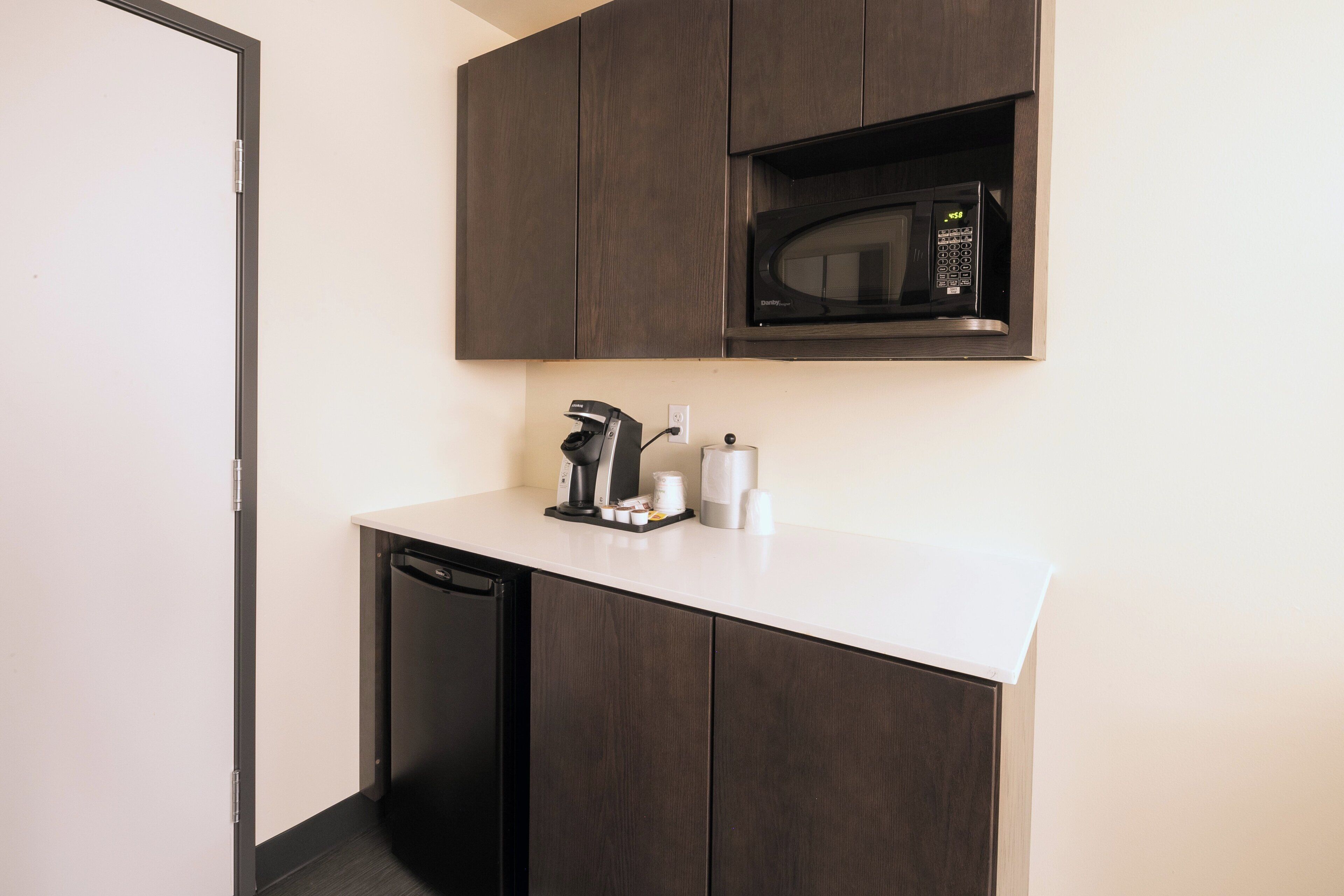 A compact kitchen with a built-in microwave, a coffee machine, and a dishwasher.