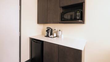 Una cocina compacta con microondas integrado, cafetera y lavavajillas.