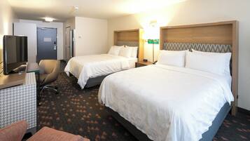 A hotel room with two beds, a desk with a television, and a chair.