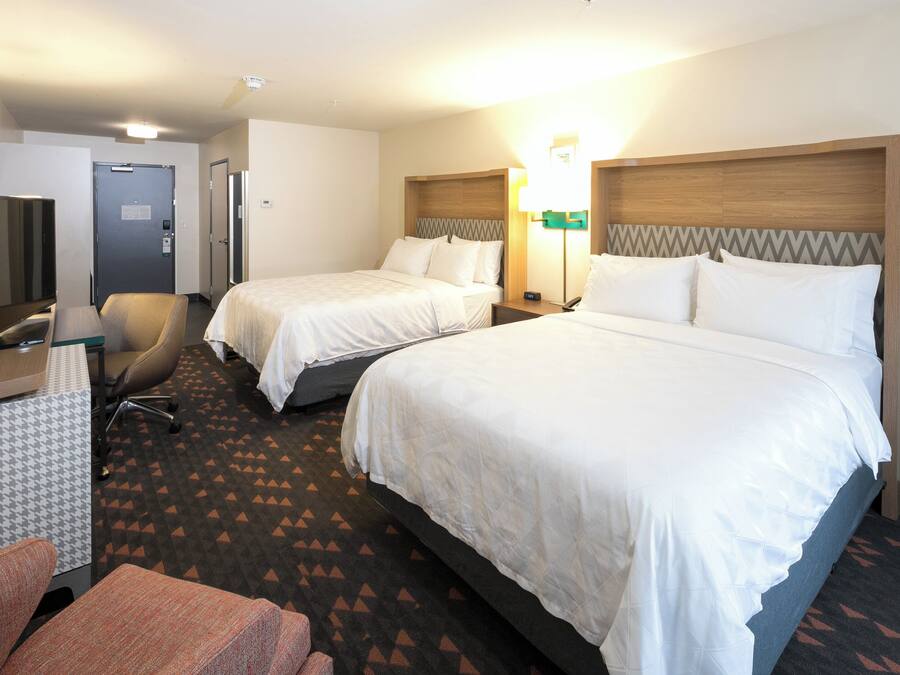 A hotel room with two beds, a desk with a television, and a chair.