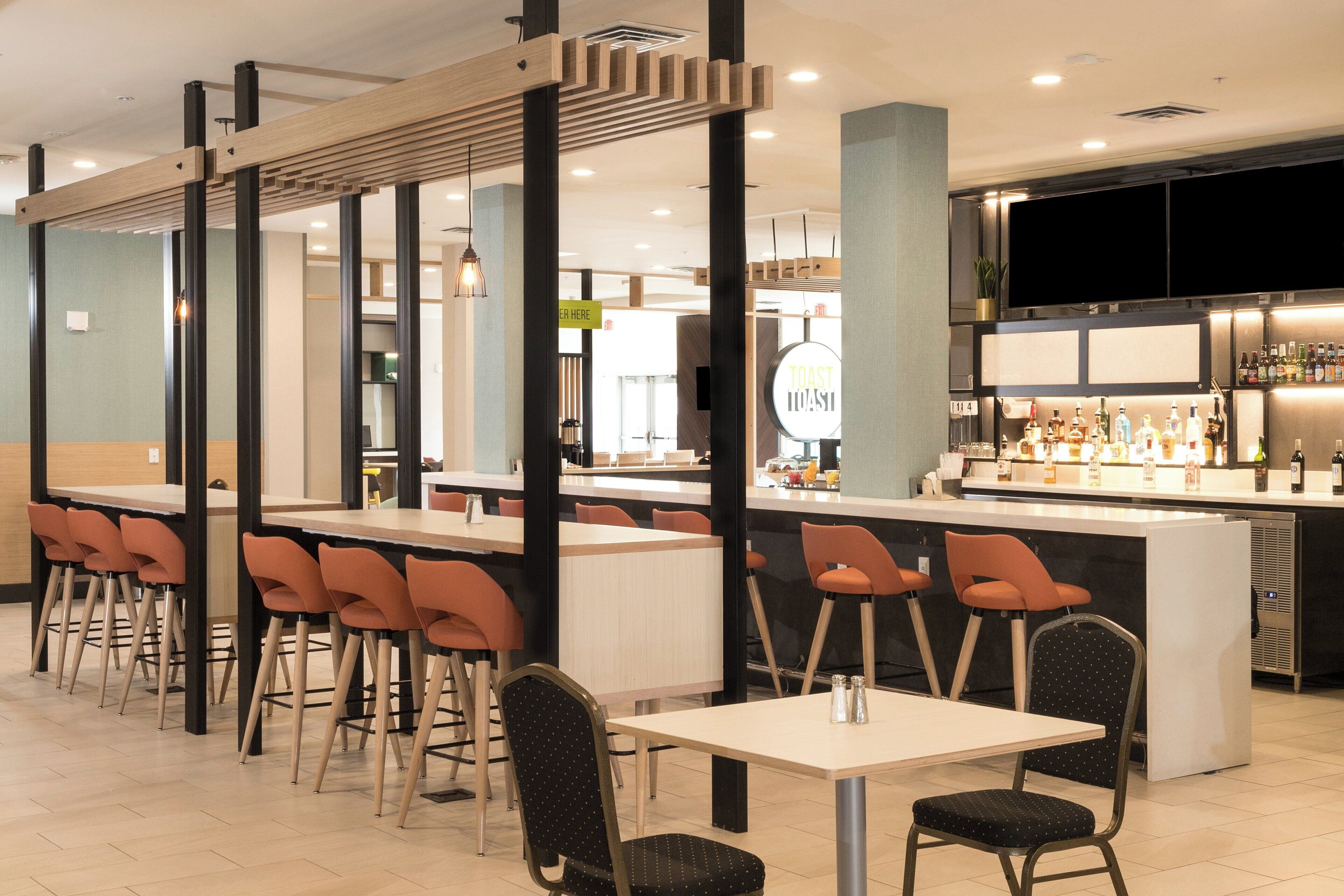 A modern bar area with a counter, seating, and a sign indicating a toast bar.