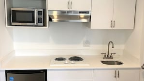 A compact kitchen with a microwave, stove, sink, and dishwasher. - Spinnaker Inn of Naples (Naples)